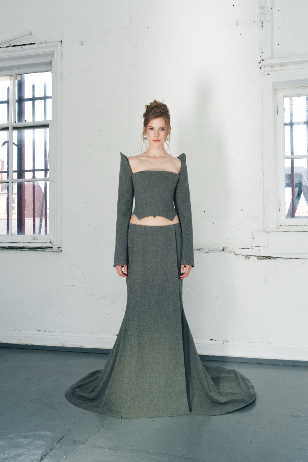 The grey bustier, full length from the front, the fishtail skirt spread on the floor
