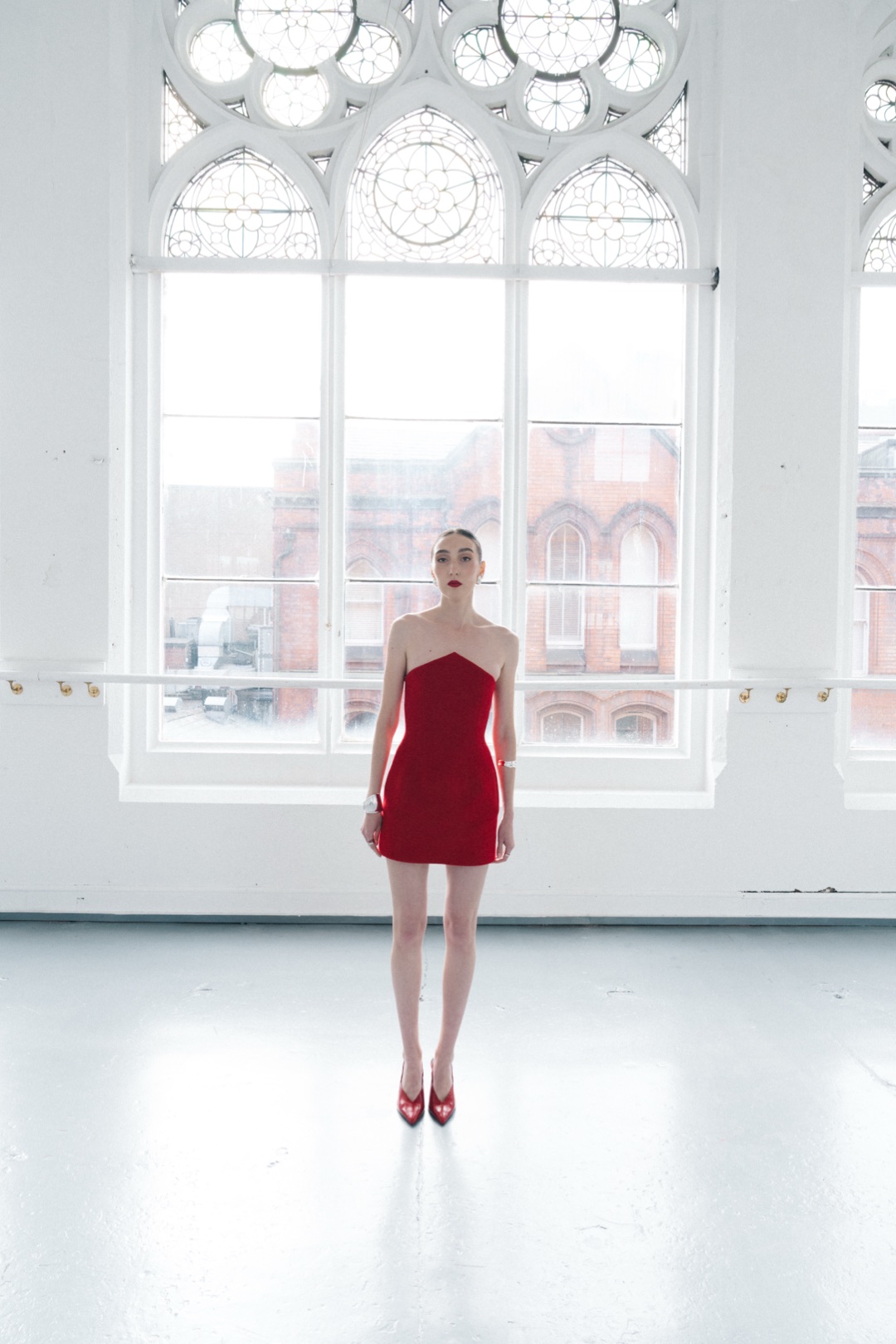 The red mini, full length beneath tall arched tracery windows