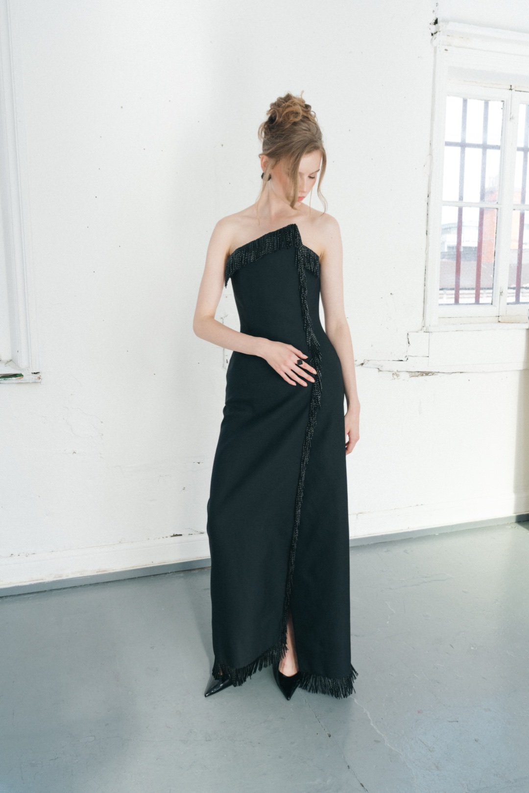 The fringe gown, head bowed, the front split opening at the beaded hem