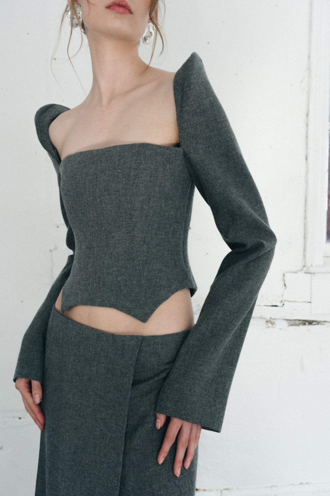The grey bustier, close-up of the bustier, its pointed hem over the skirt