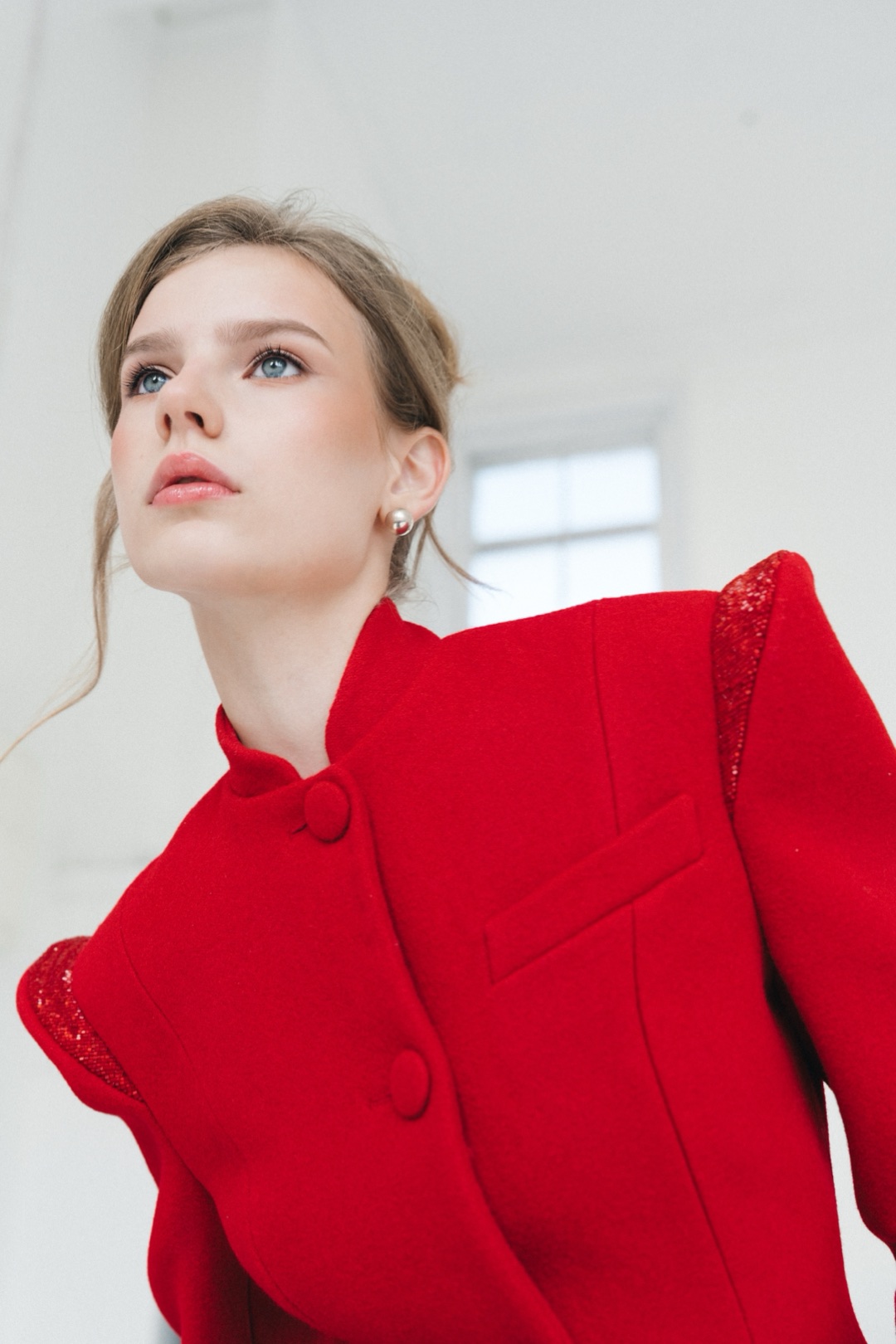 The red coat, seen from below, stand collar, covered buttons and welt pocket