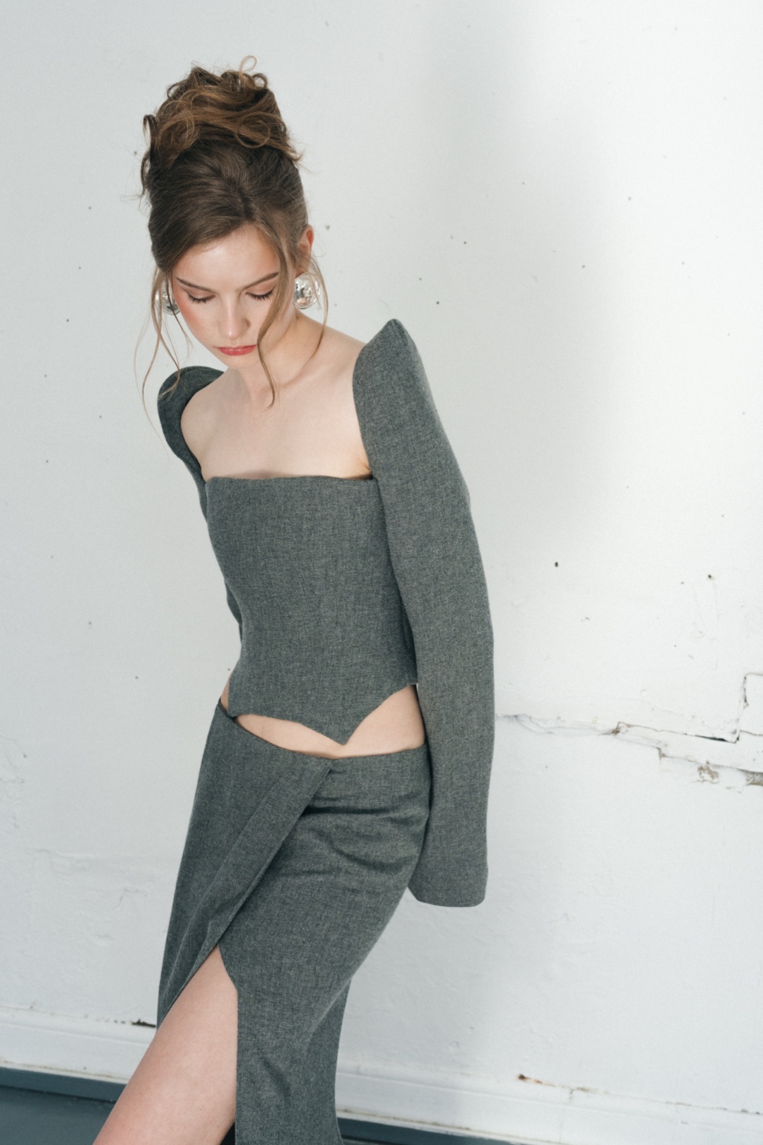 The grey bustier, looking down mid-step, the skirt wrapping into its front opening