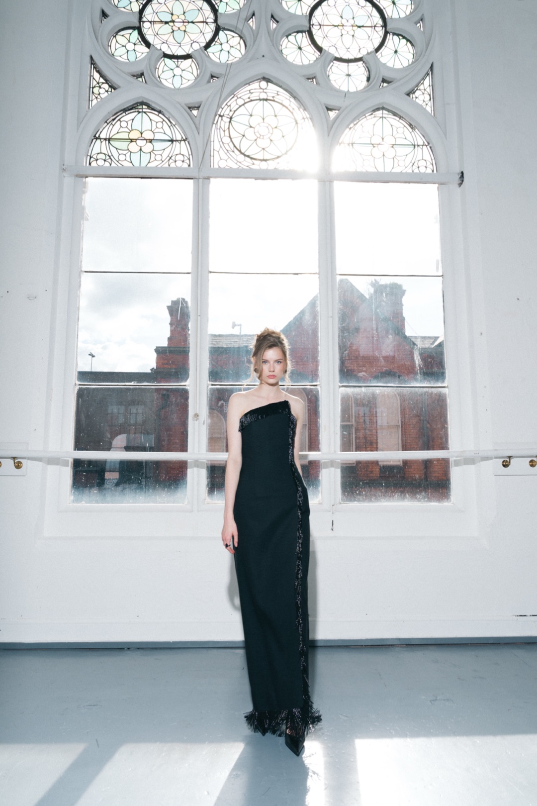 The fringe gown, full length beneath an arched stained glass window