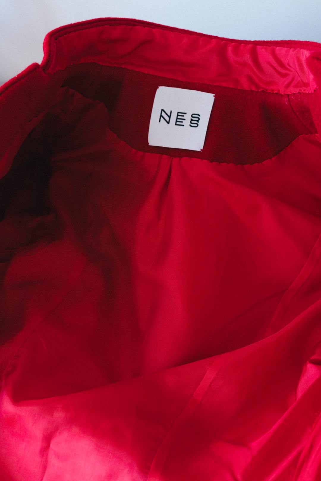 The red coat, inside the collar, with the atelier label and red lining